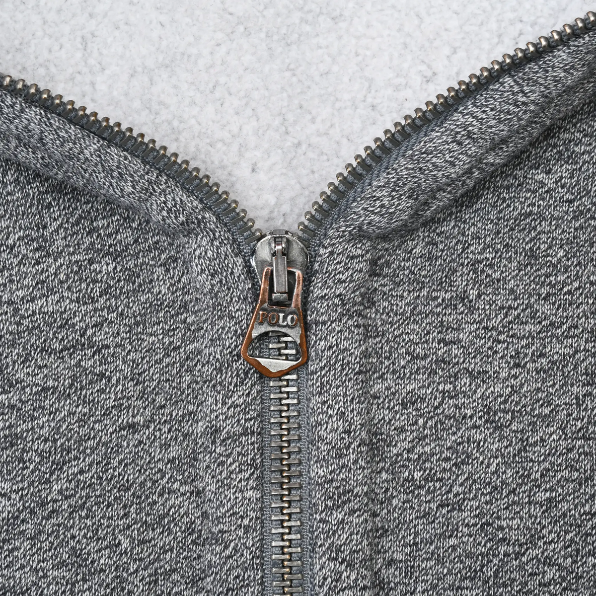 Close-up of metal zipper and Polo-branded pull on grey Ralph Lauren hoodie