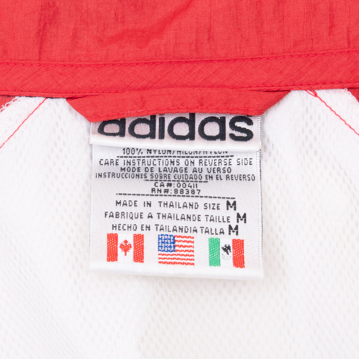 Adidas interior care label showing size medium and country flag graphics