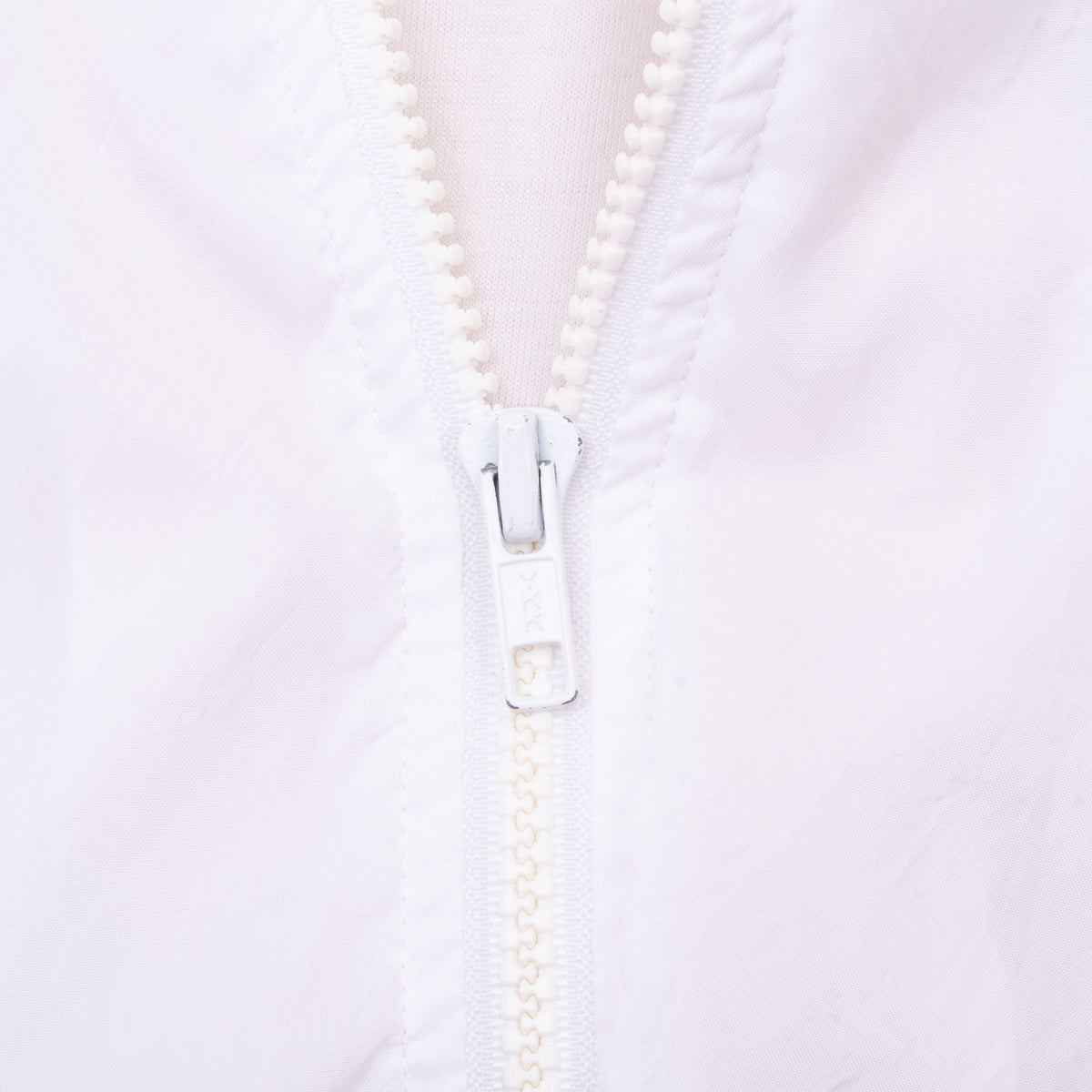 Close-up of white front zipper and surrounding jacket fabric