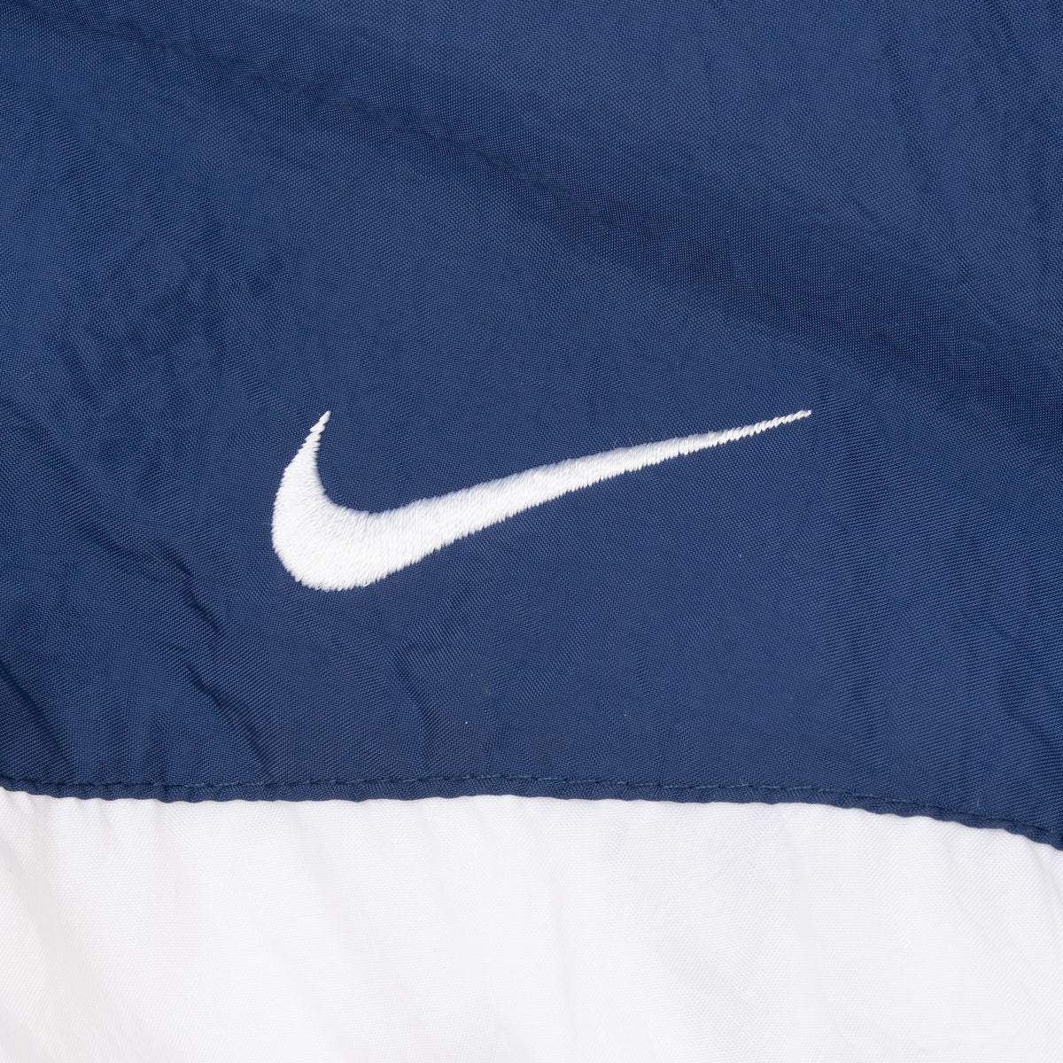 White embroidered Nike Swoosh on navy chest panel