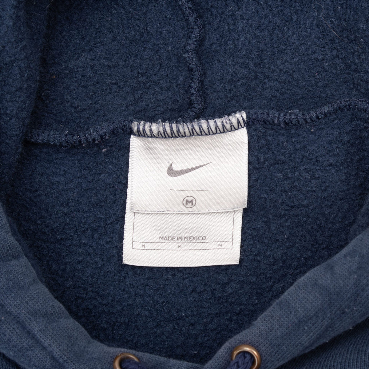 Nike neck tag inside navy blue hoodie showing medium size and Made in Mexico text