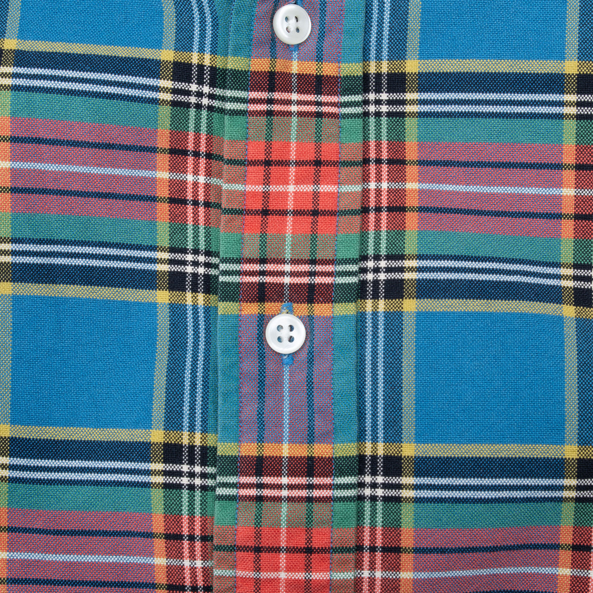 Close-up of white buttons and multicolor plaid pattern on shirt front