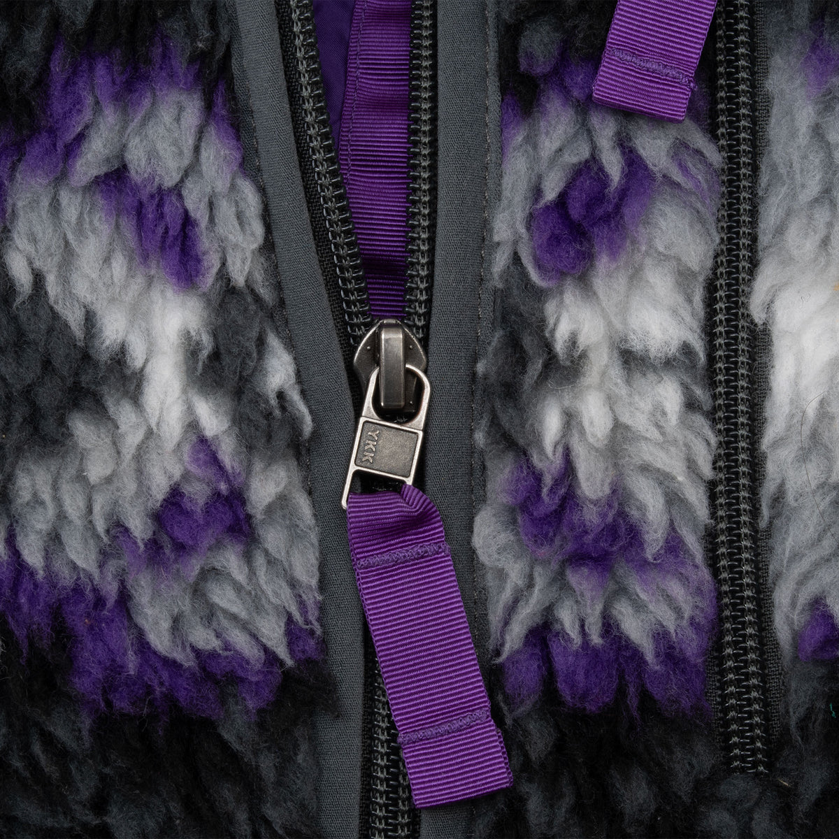 Close-up of jacket zippers with purple grosgrain pull tabs