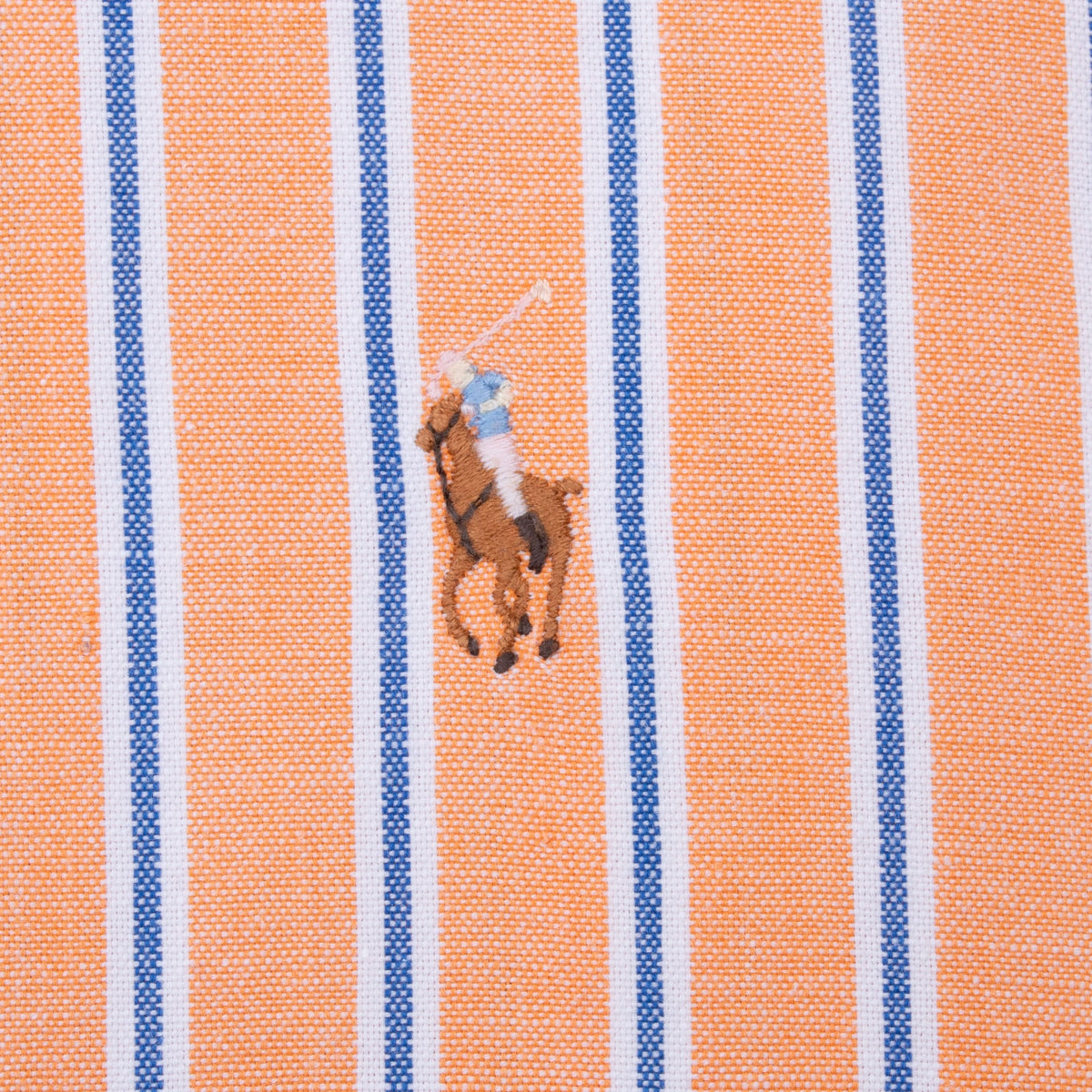 Close-up of embroidered Polo pony on peach, blue and white striped shirt chest