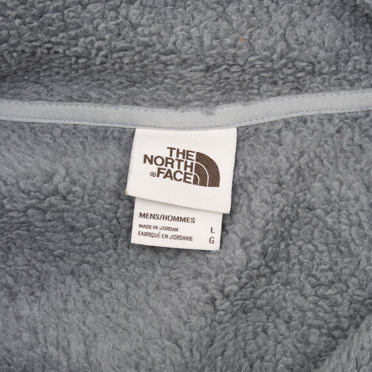 The North Face neck label and men's size large tag inside grey jacket