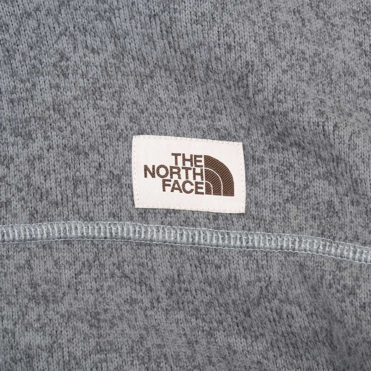 The North Face logo patch and contrast stitching on grey jacket chest