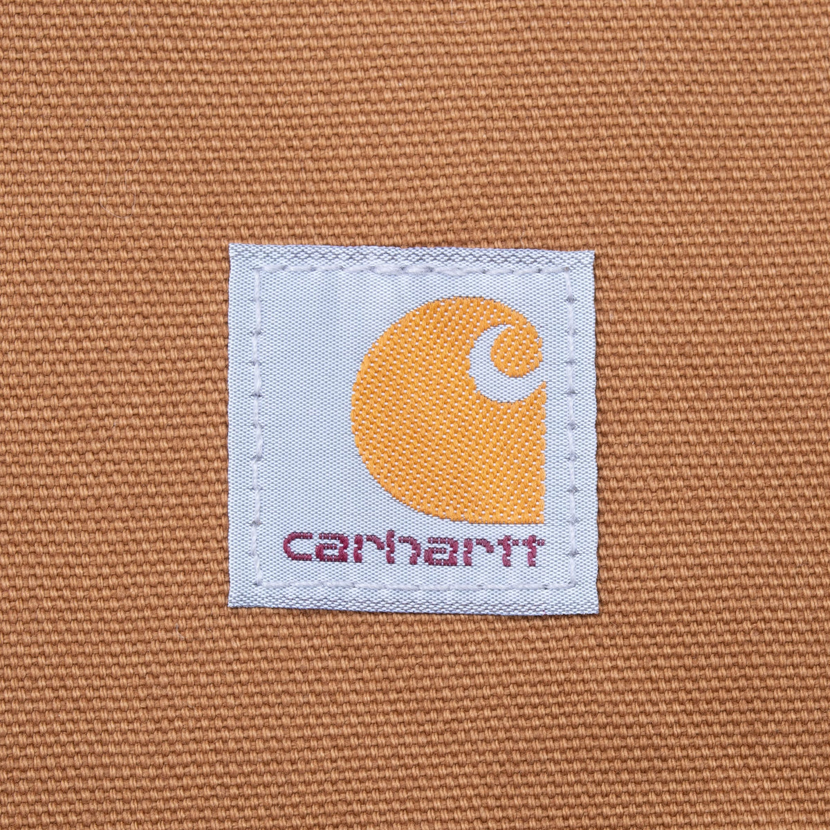 Close-up of Carhartt logo patch stitched onto brown vest pocket