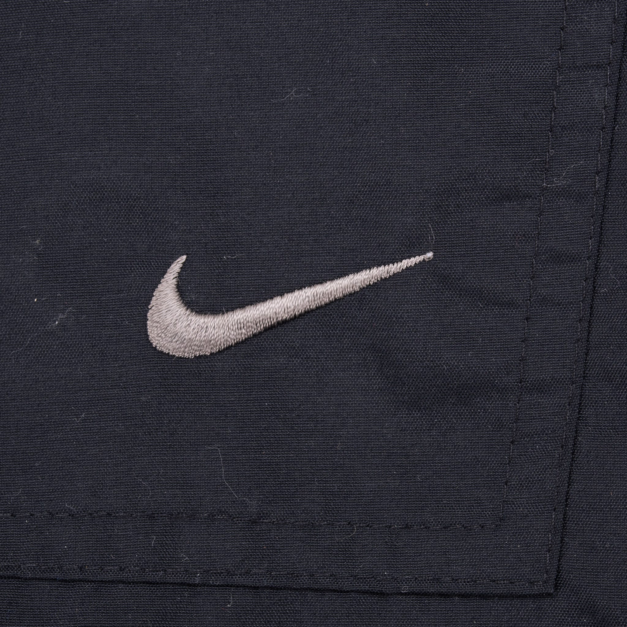 Close-up of silver Nike Swoosh embroidery on black lower-leg pocket