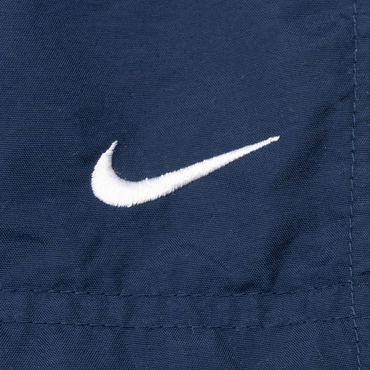 White embroidered Nike Swoosh detail on blue track pants