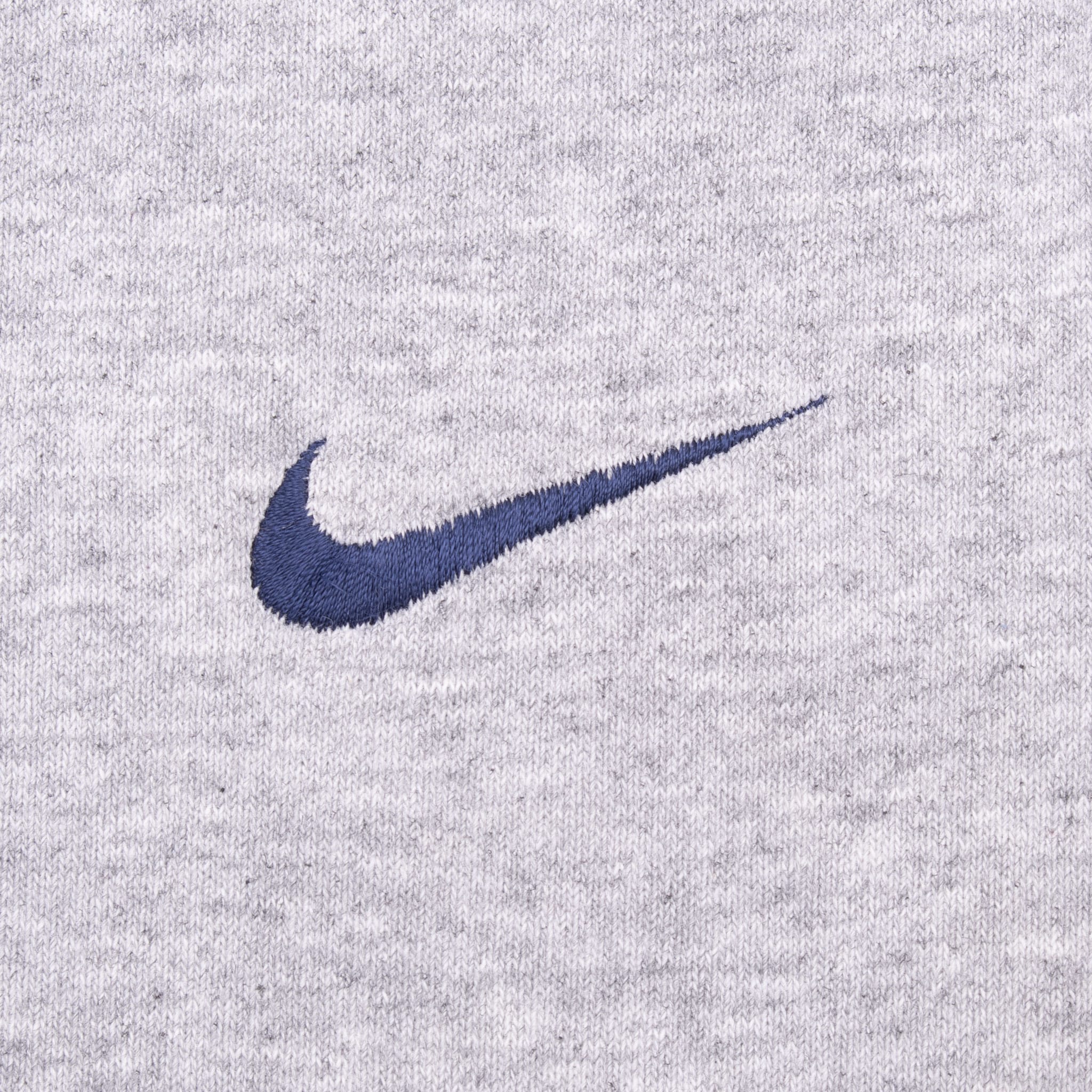 Close-up of dark blue embroidered Nike Swoosh on grey fabric