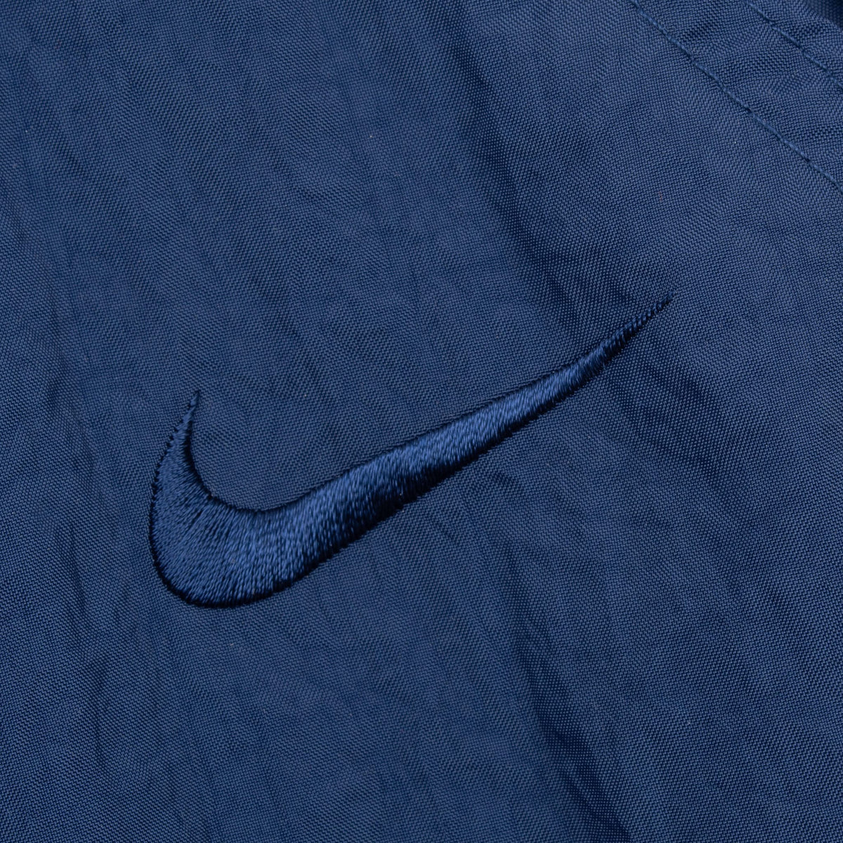 Close-up of tonal blue Nike Swoosh embroidery on track pants