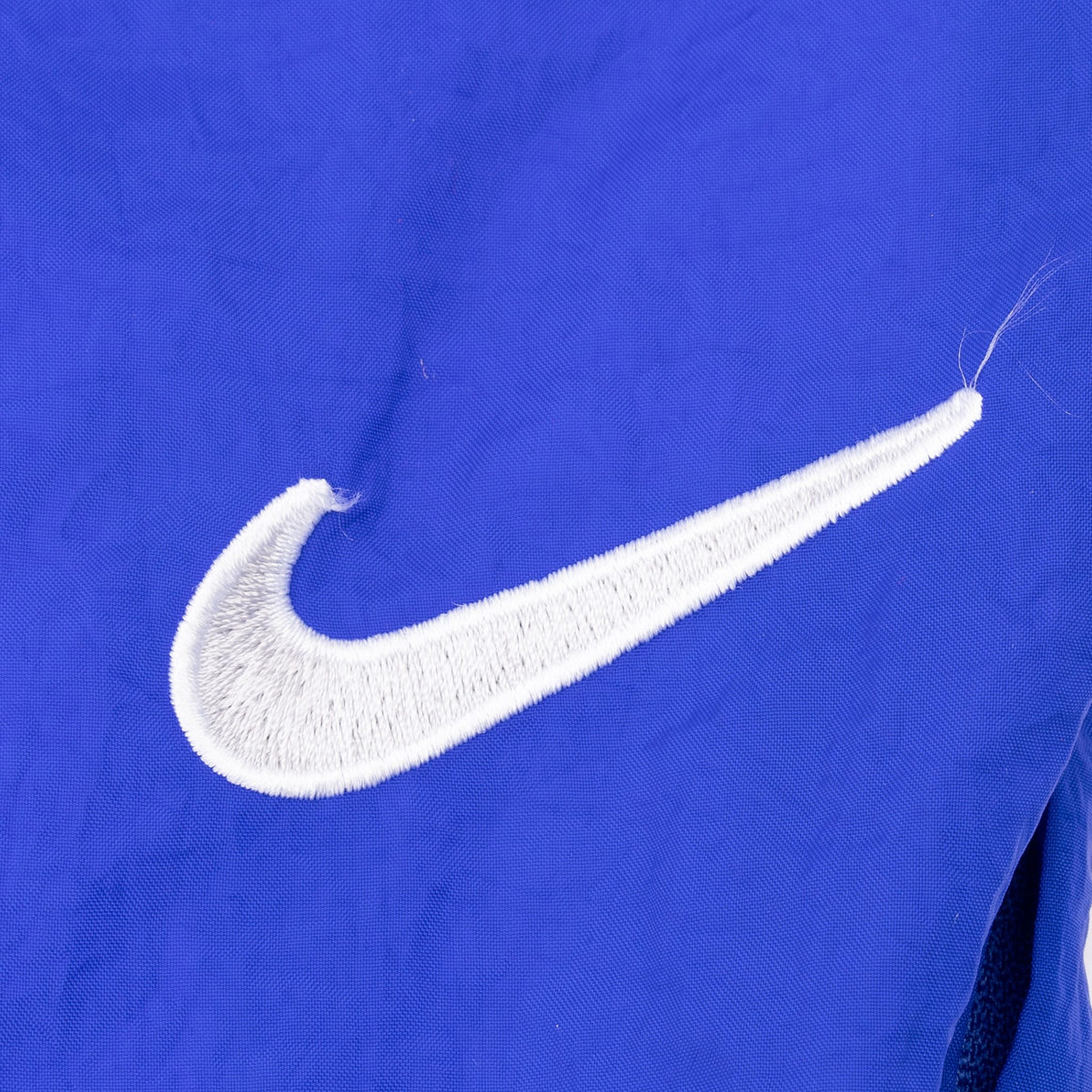 White embroidered Nike Swoosh detail on blue-purple track pants