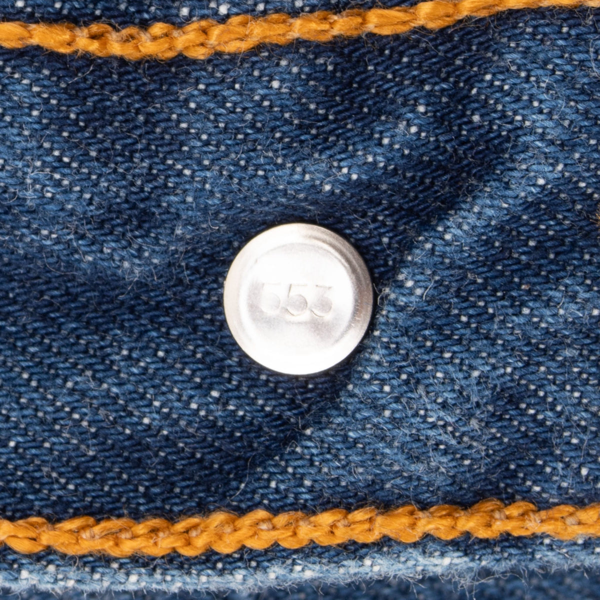 Close-up of Levi's jeans back button stamped 553 with orange stitching