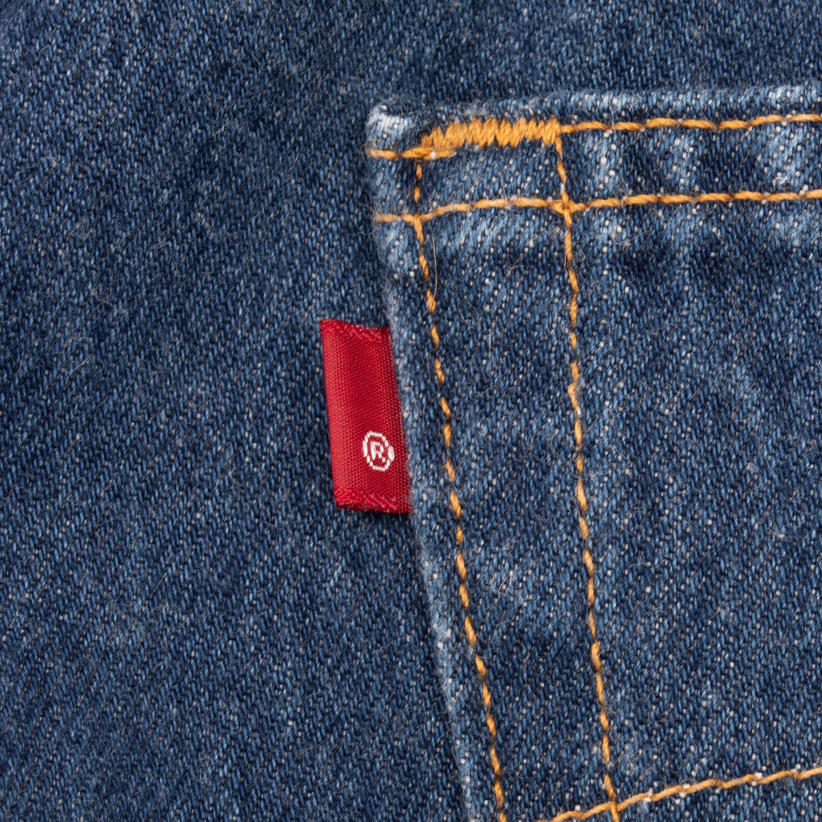 Close-up of Levi's red tab beside a rear pocket with orange contrast stitching