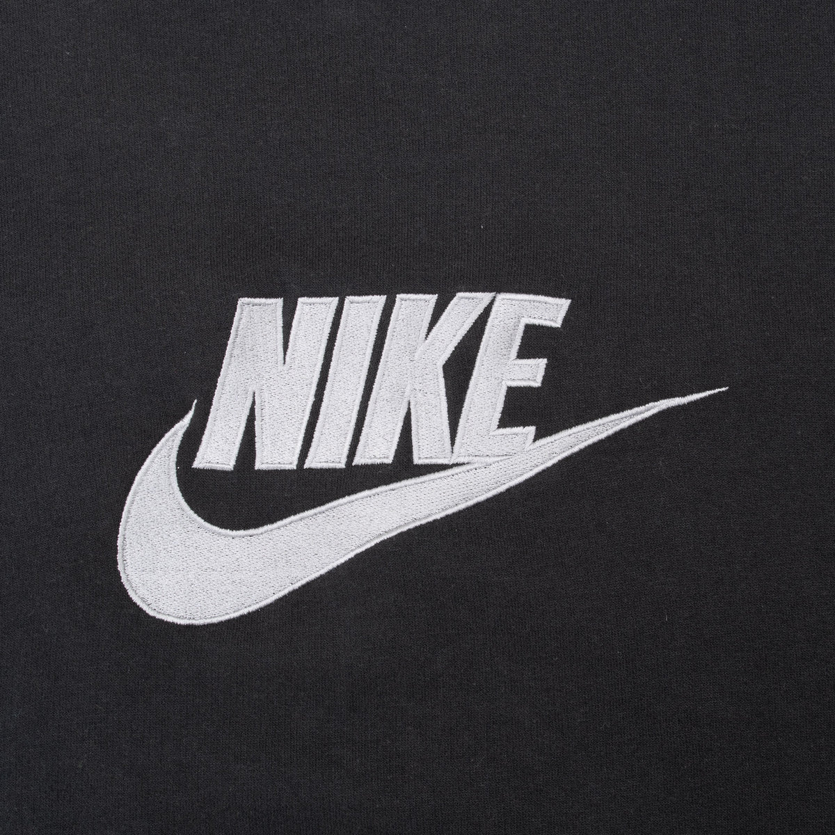 Close-up of white Nike Swoosh embroidery on black sweatshirt