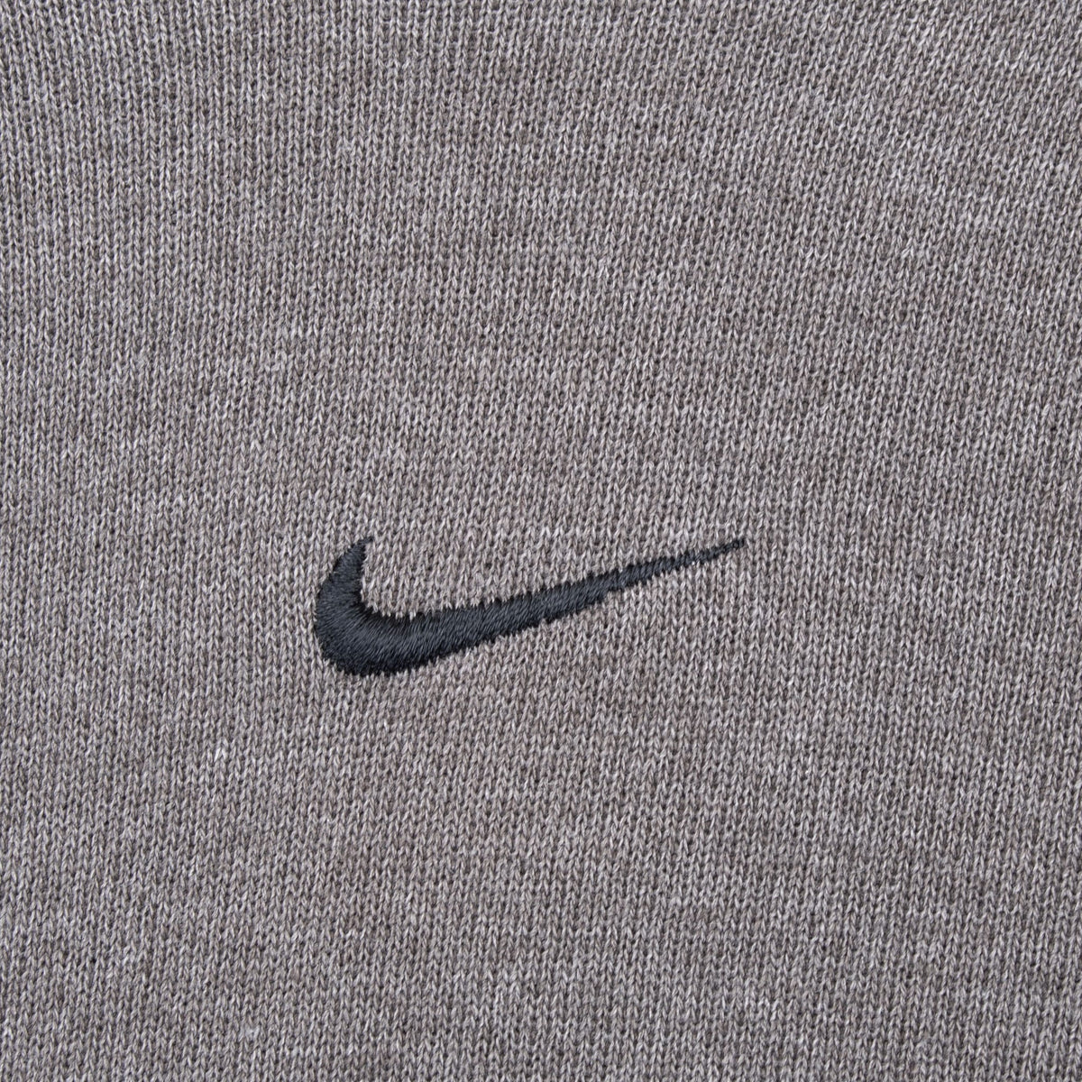 Close-up of dark Nike Swoosh embroidery centered on faded grey hoodie fabric