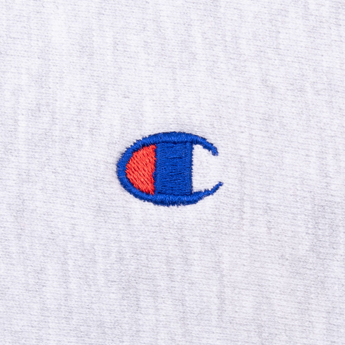 Close-up of red and blue Champion C logo embroidery on grey fabric