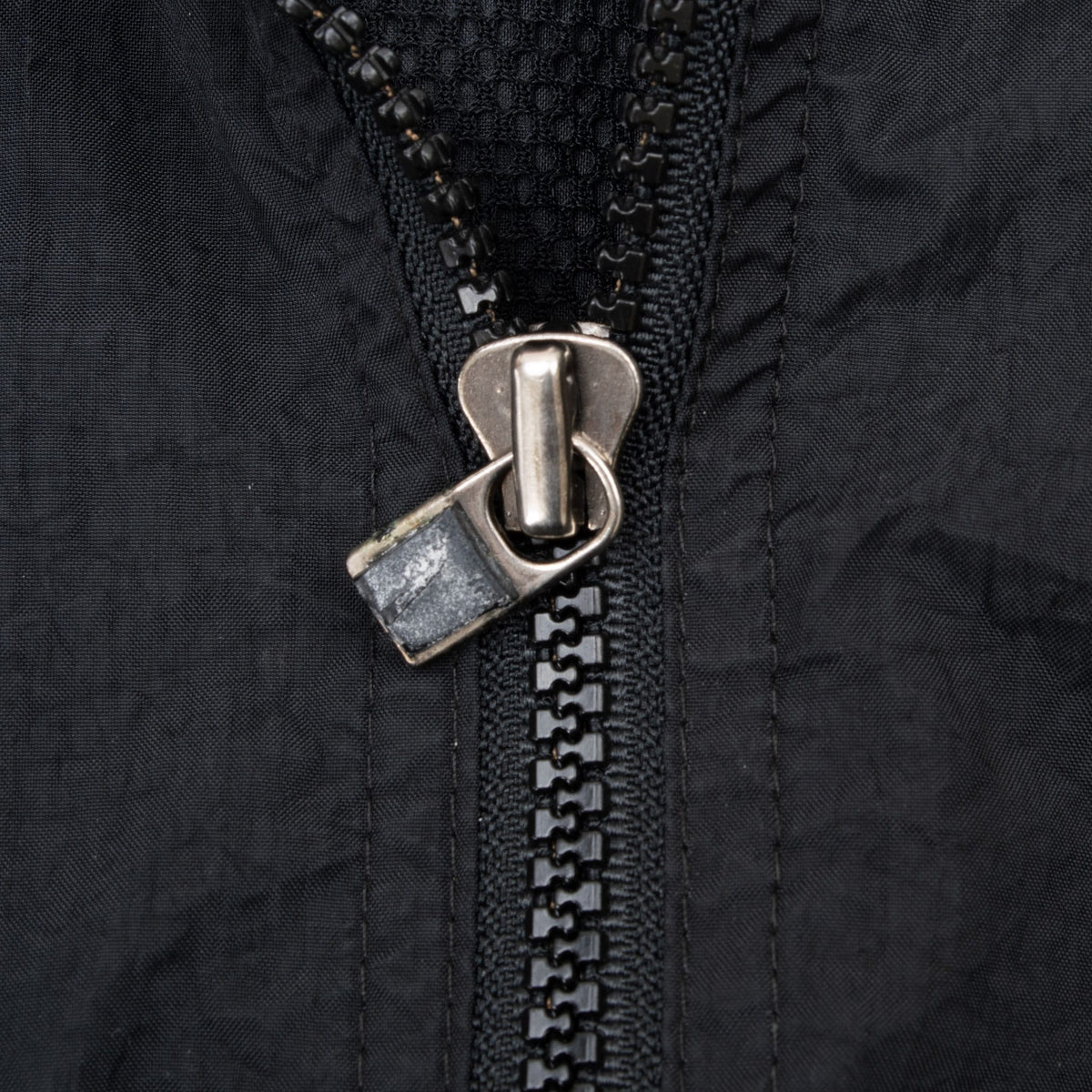 Close-up of metal zipper pull and black front zipper on Nike windbreaker