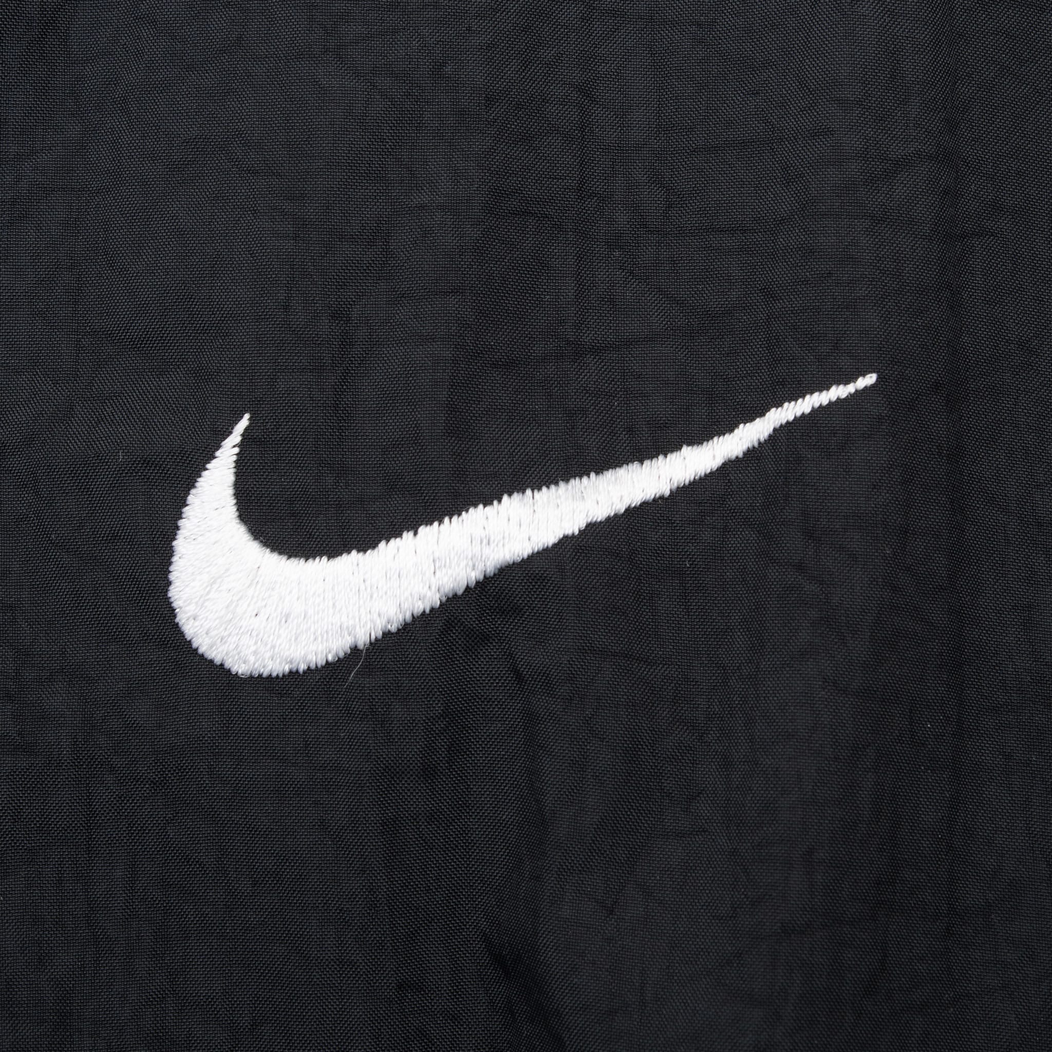 Close-up of white embroidered Nike Swoosh on black chest fabric