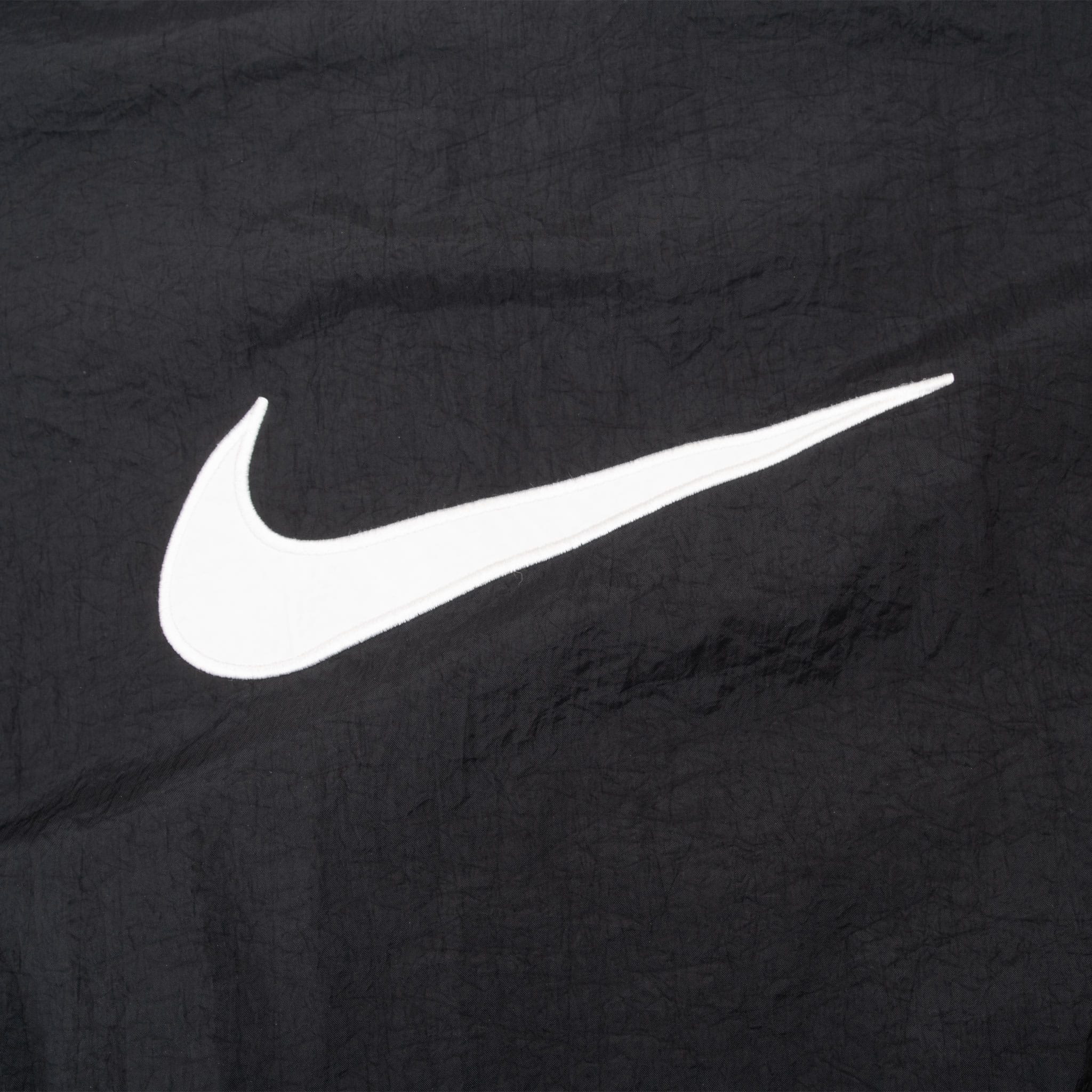 Close-up of oversized white Nike Swoosh on black back fabric