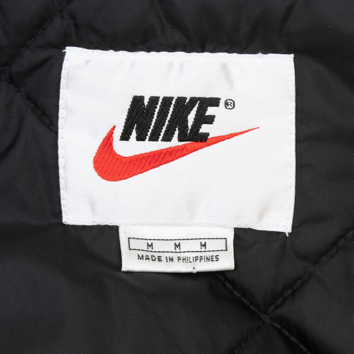 Nike neck label and medium size tag inside black quilted jacket lining