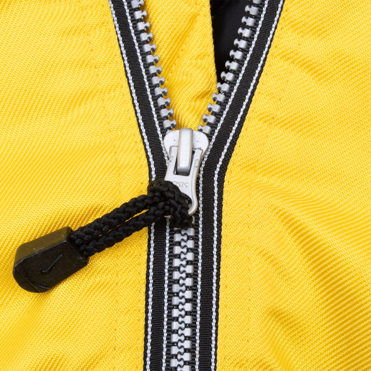 Close-up of black-and-white front zipper and cord pull on yellow Nike jacket