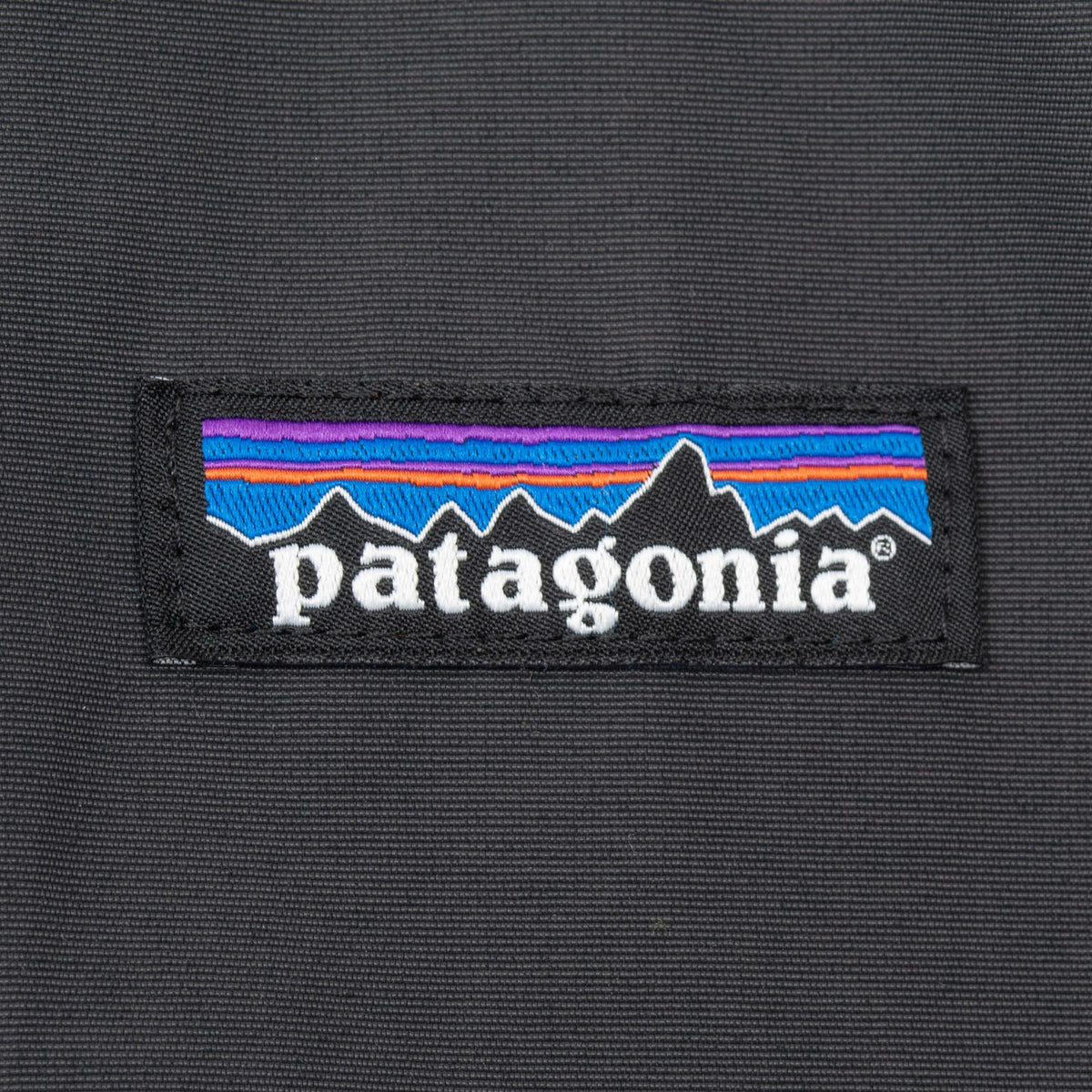 Close-up of woven Patagonia mountain logo patch on dark grey jacket chest