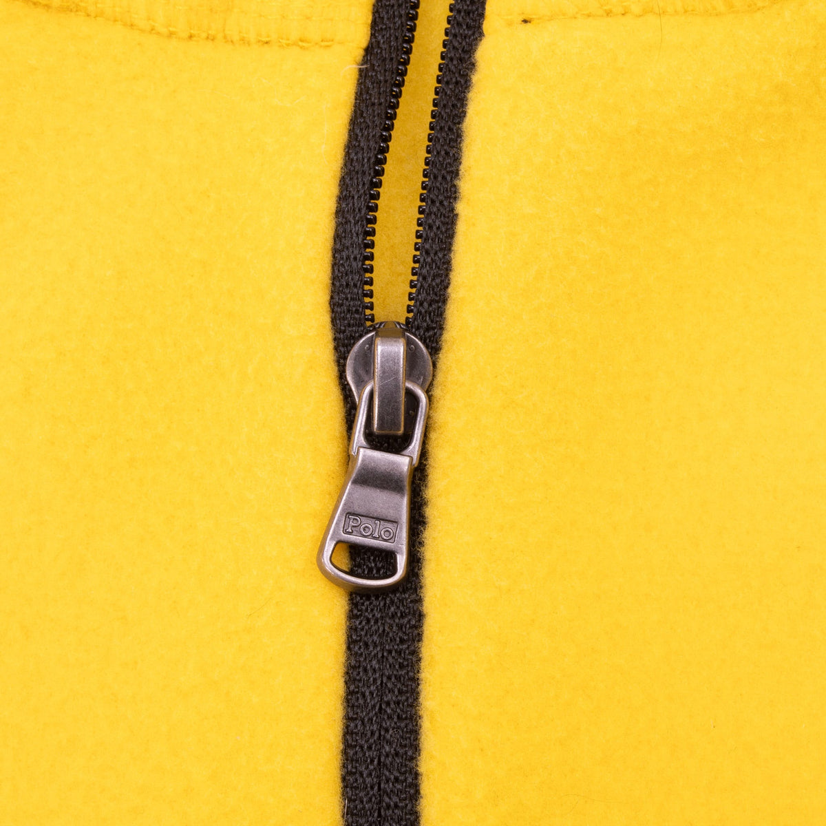 Close-up of black quarter-zip closure and Polo-branded metal pull on yellow fleece