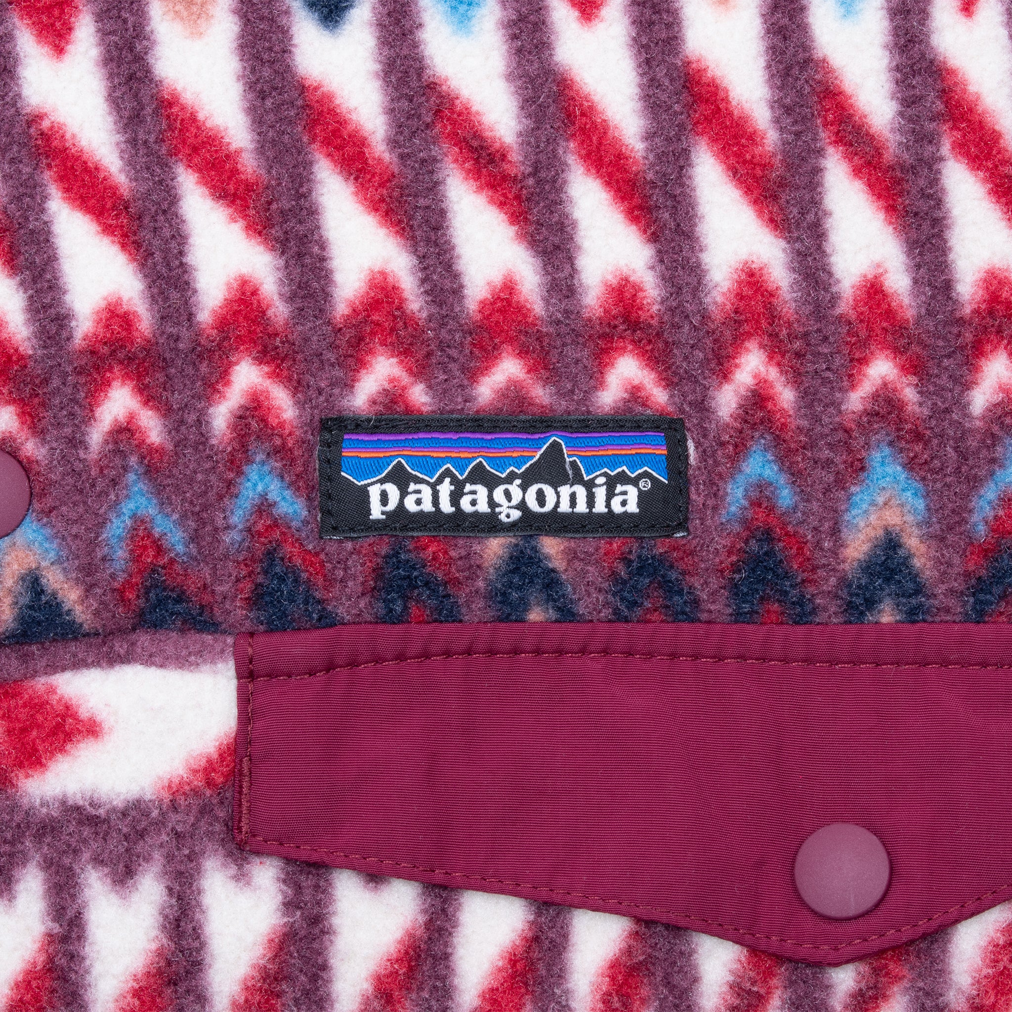 Patagonia logo and burgundy snap chest pocket detail on geometric-print fleece