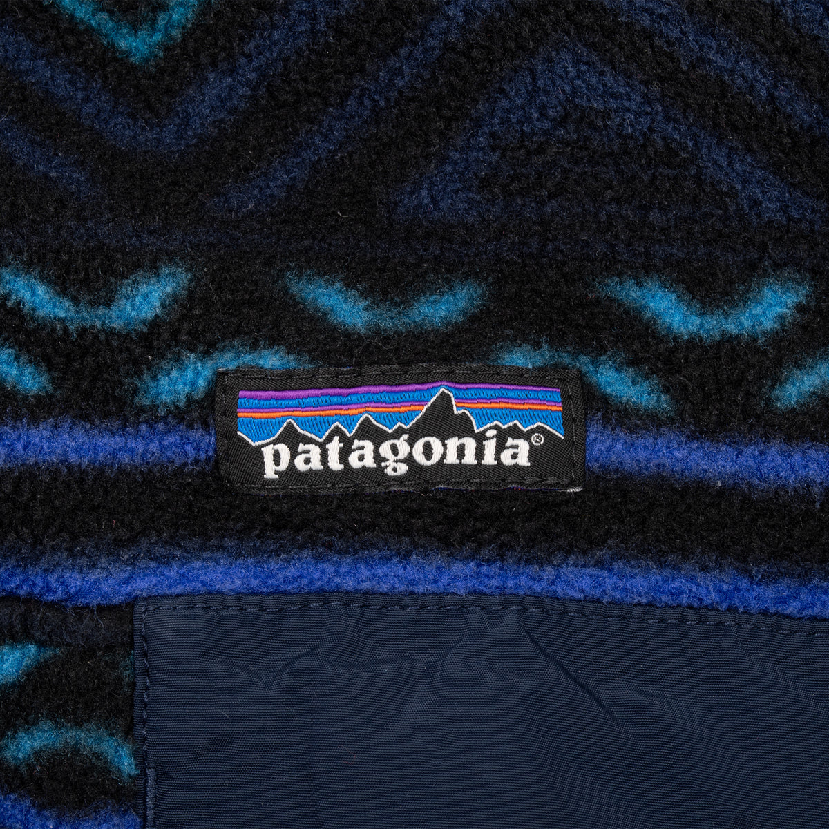 Patagonia logo label above the navy chest pocket on patterned fleece