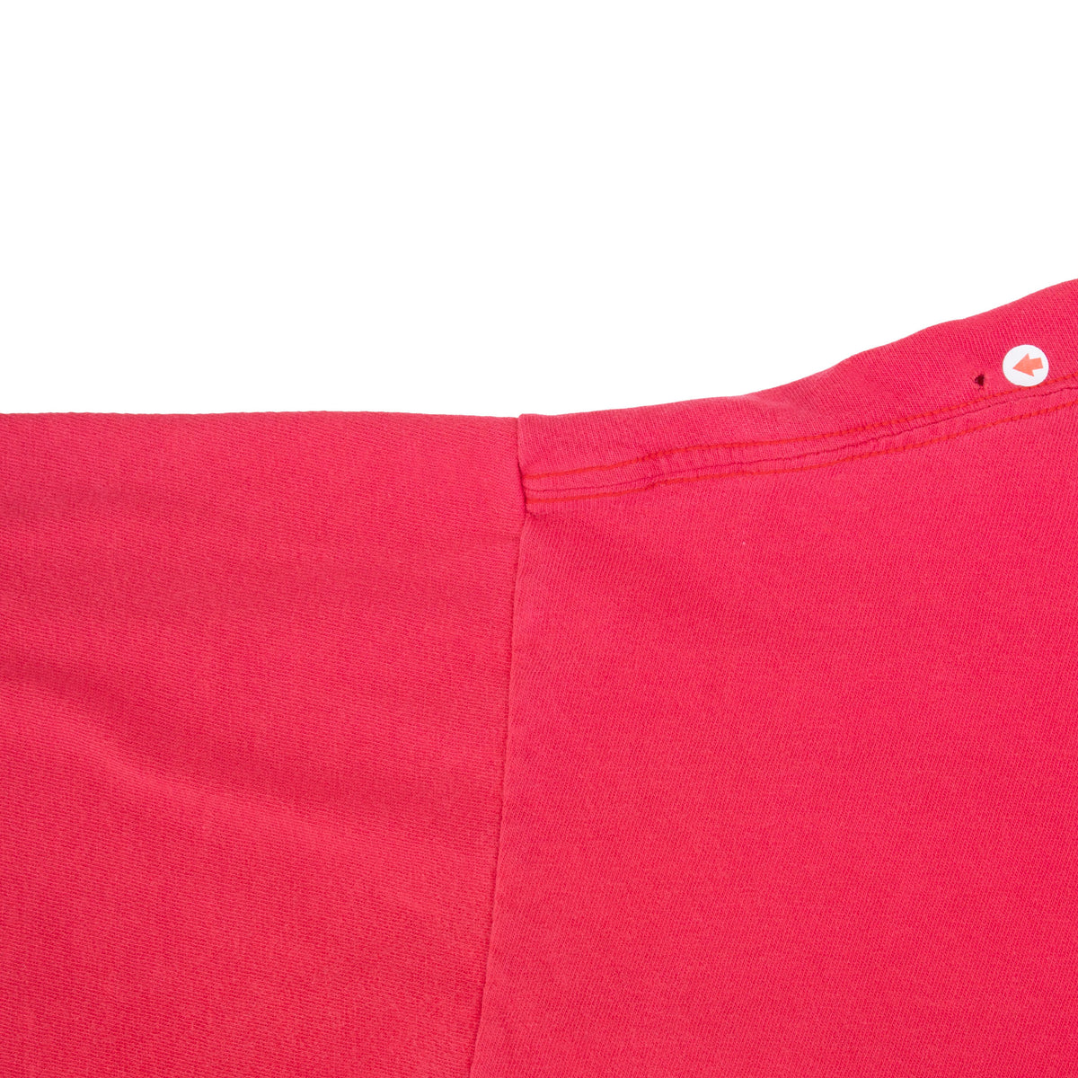 Close-up of a small hole near the shoulder seam of the red Nike T-shirt