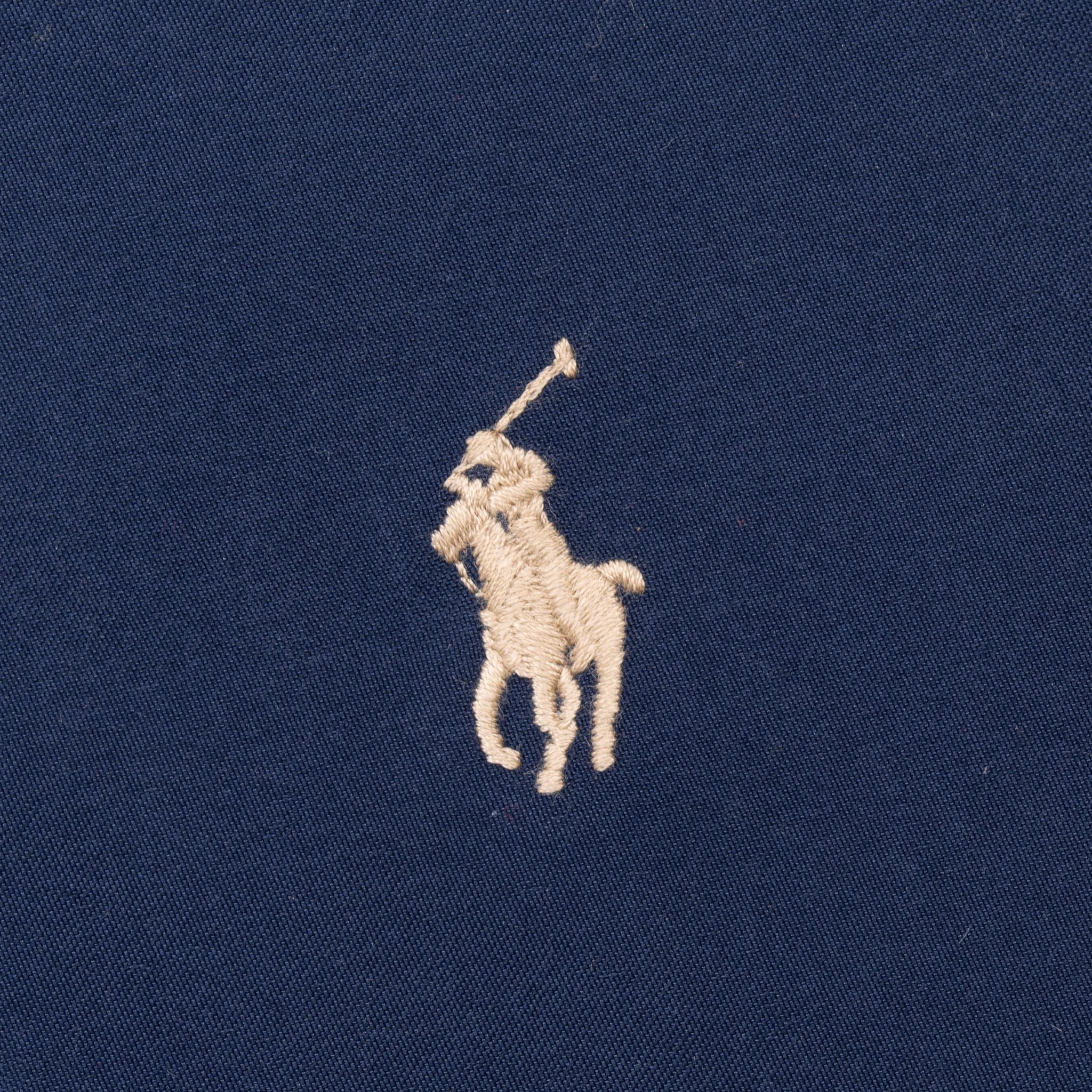 Close-up of beige Polo pony embroidery on blue jacket chest