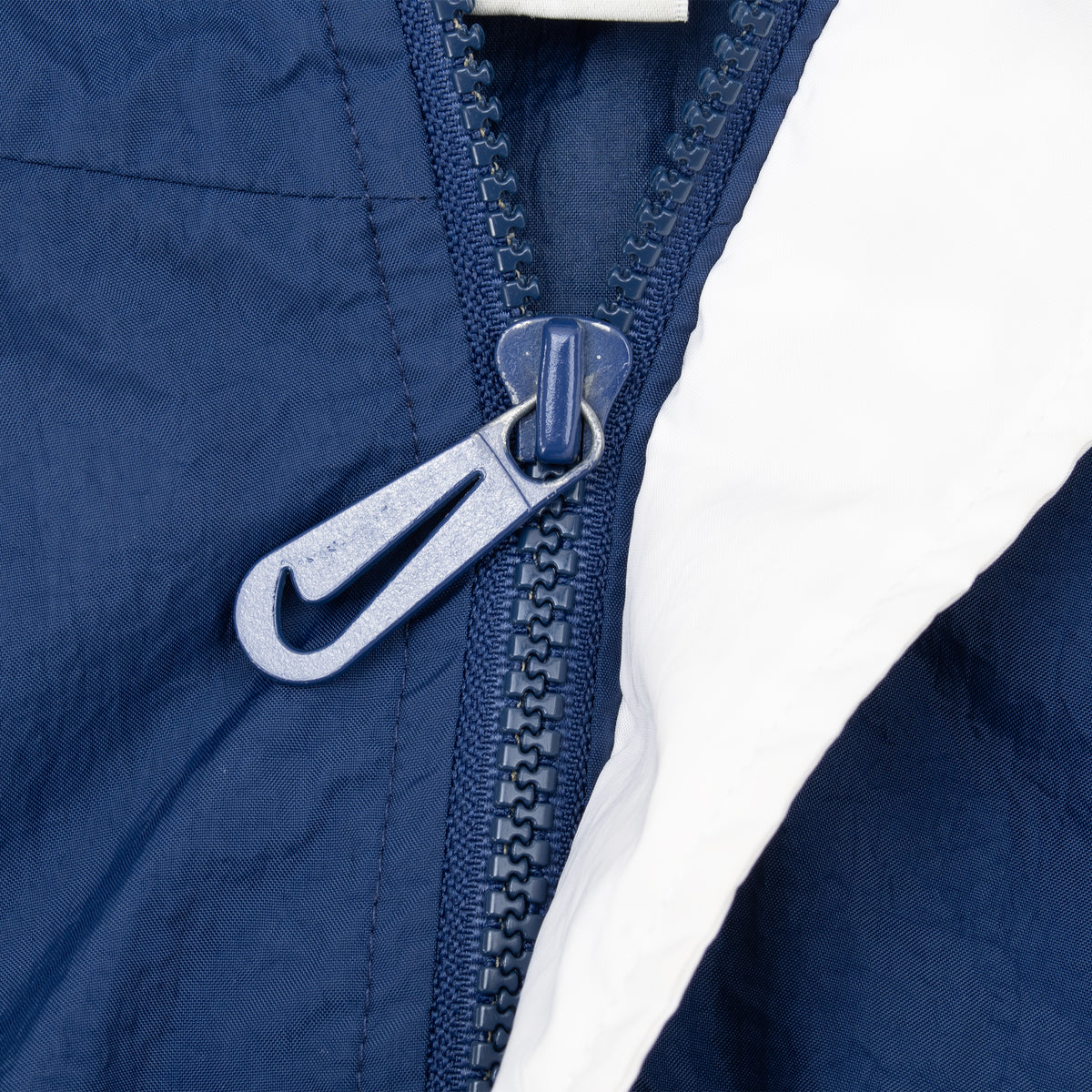 Close-up of blue half zipper with Nike Swoosh pull on windbreaker