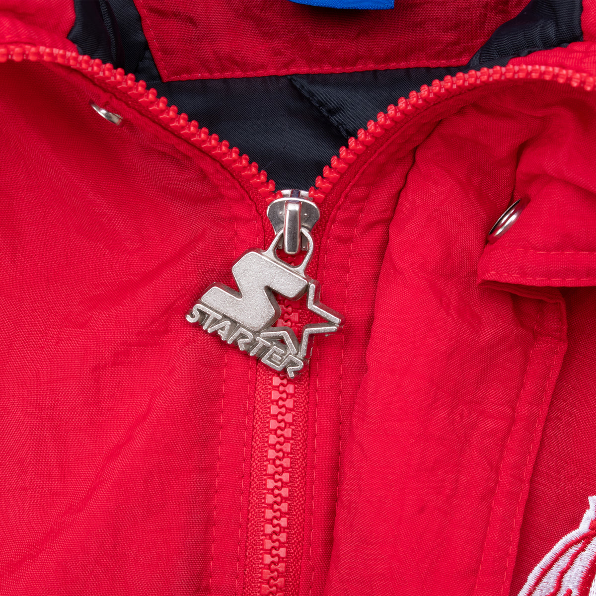 Close-up of silver Starter logo zipper pull on red University of Utah jacket