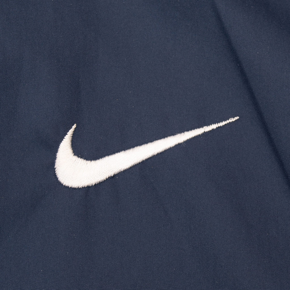 Close-up of white embroidered Nike Swoosh on blue fabric