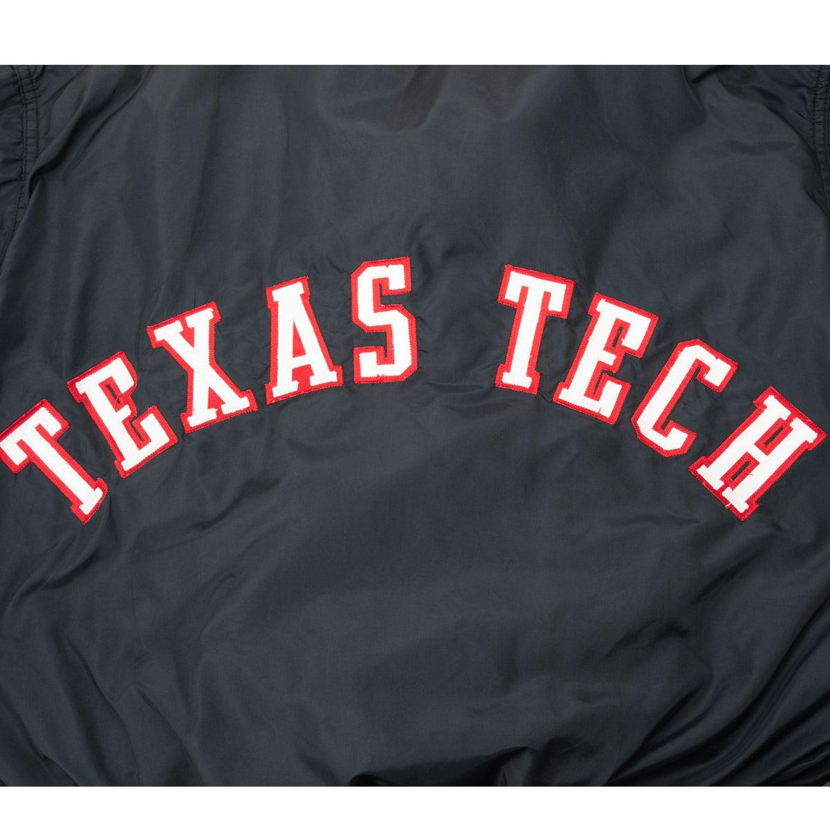 Close-up of arched white Texas Tech lettering with red borders on jacket back