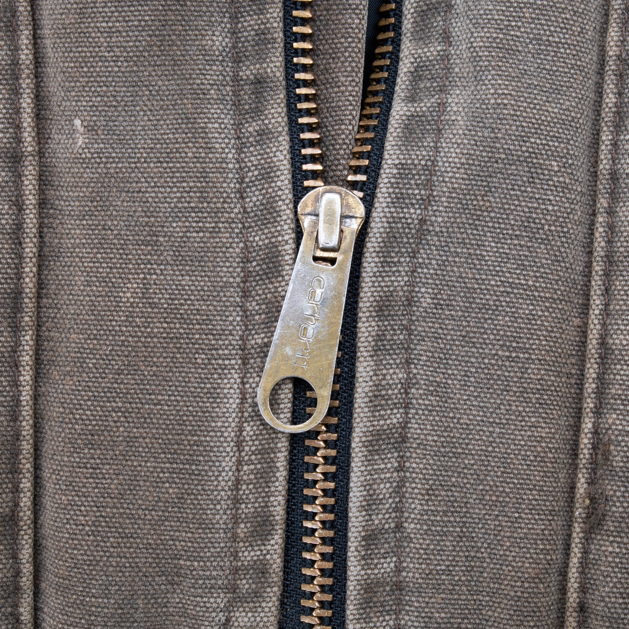 Close-up of Carhartt-branded metal zipper on brown vest fabric