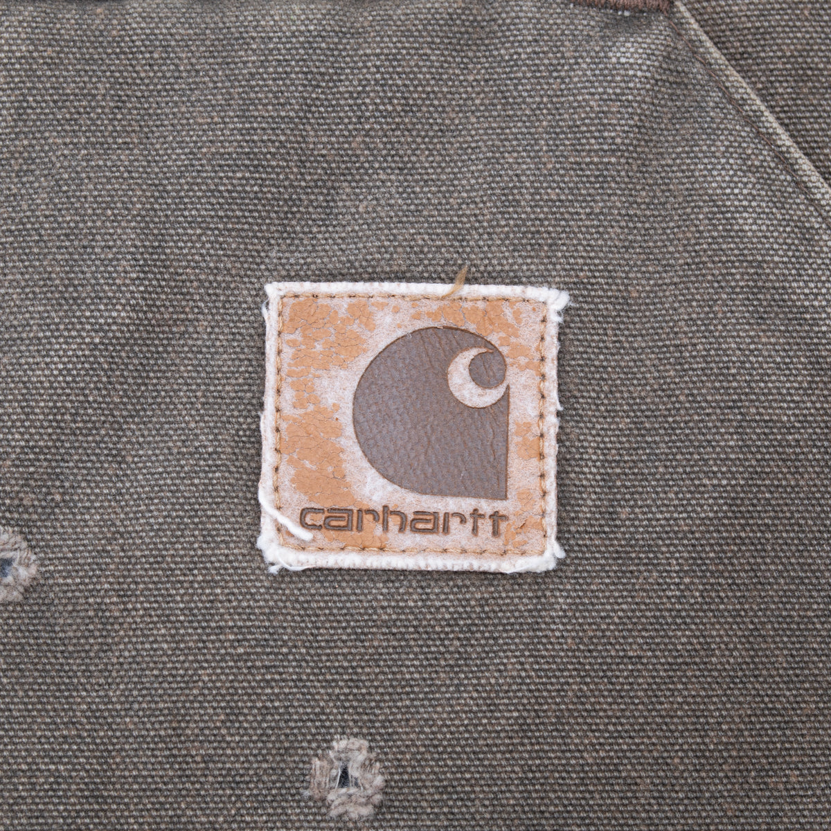 Close-up of worn Carhartt logo patch on brown vest pocket