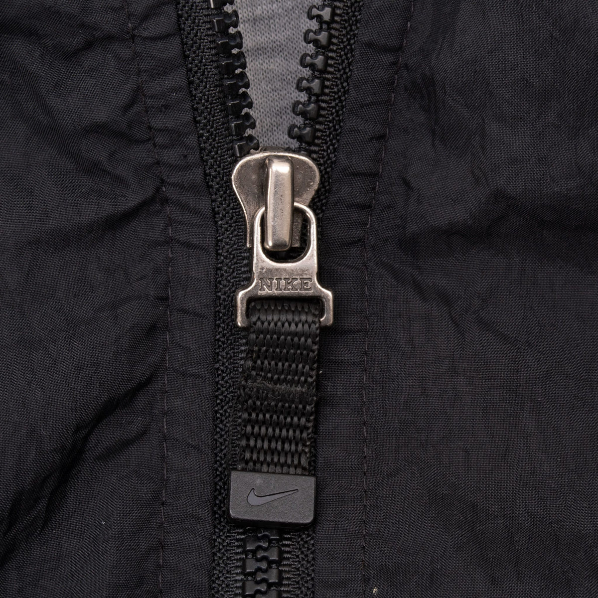 Close-up of Nike-branded zipper pull on black windbreaker