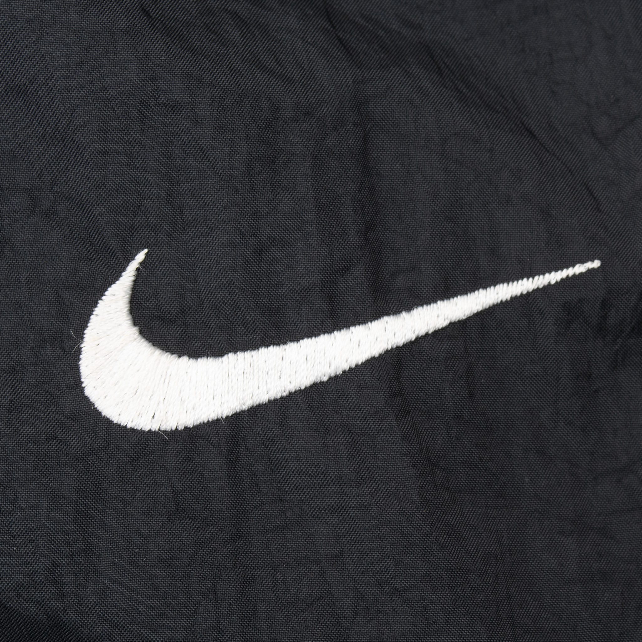 Close-up of white embroidered Nike Swoosh on black fabric