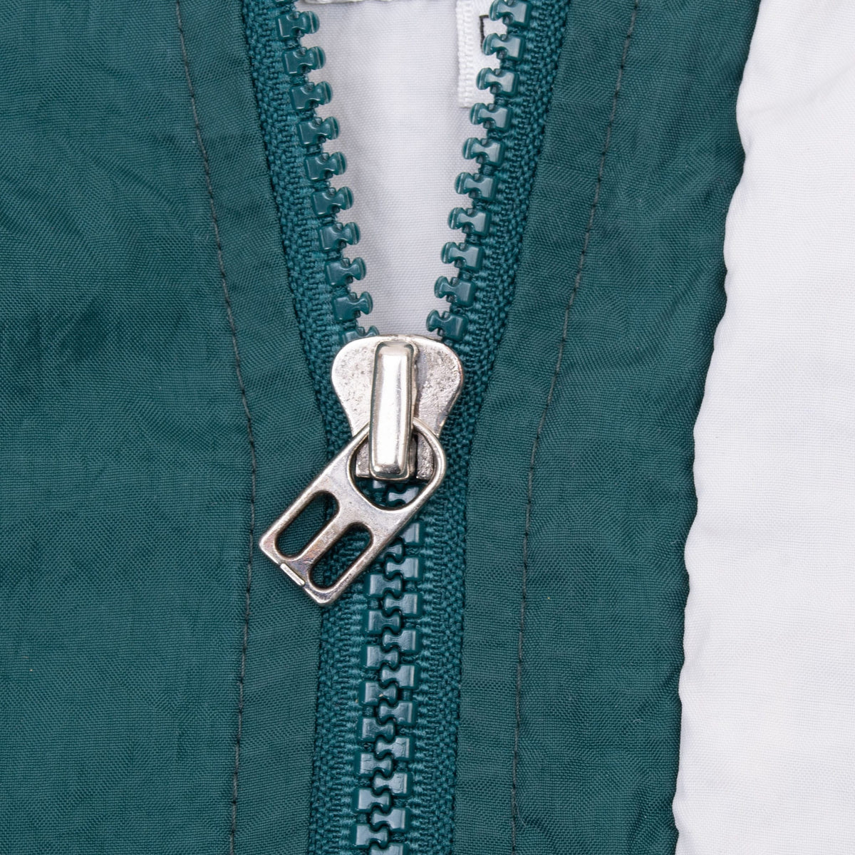 Close-up of green front zipper and silver metal zipper pull