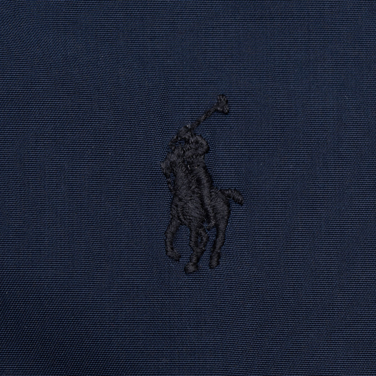 Close-up of tonal embroidered Polo pony logo on navy fabric