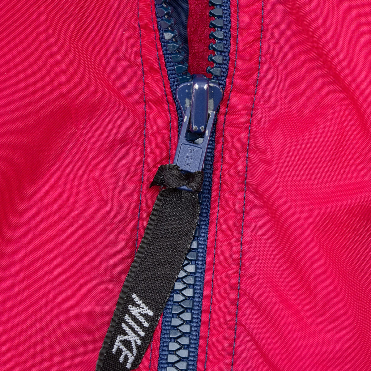 Close-up of navy front zipper and Nike-branded pull tab on pink fabric