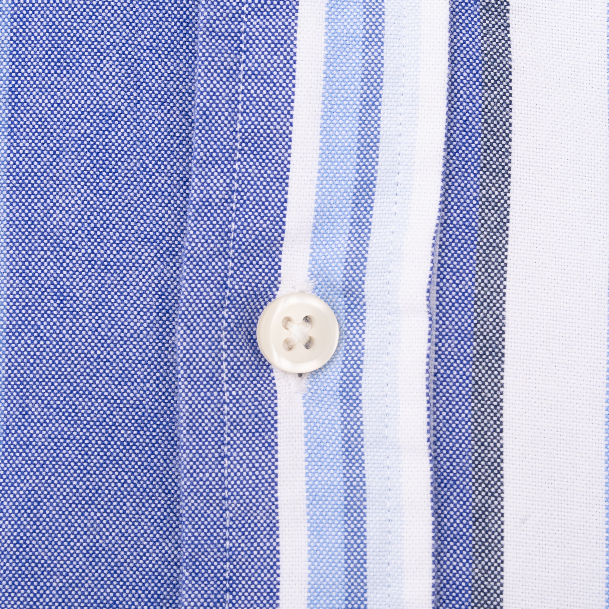 Close-up of white button and stitching on blue striped shirt fabric