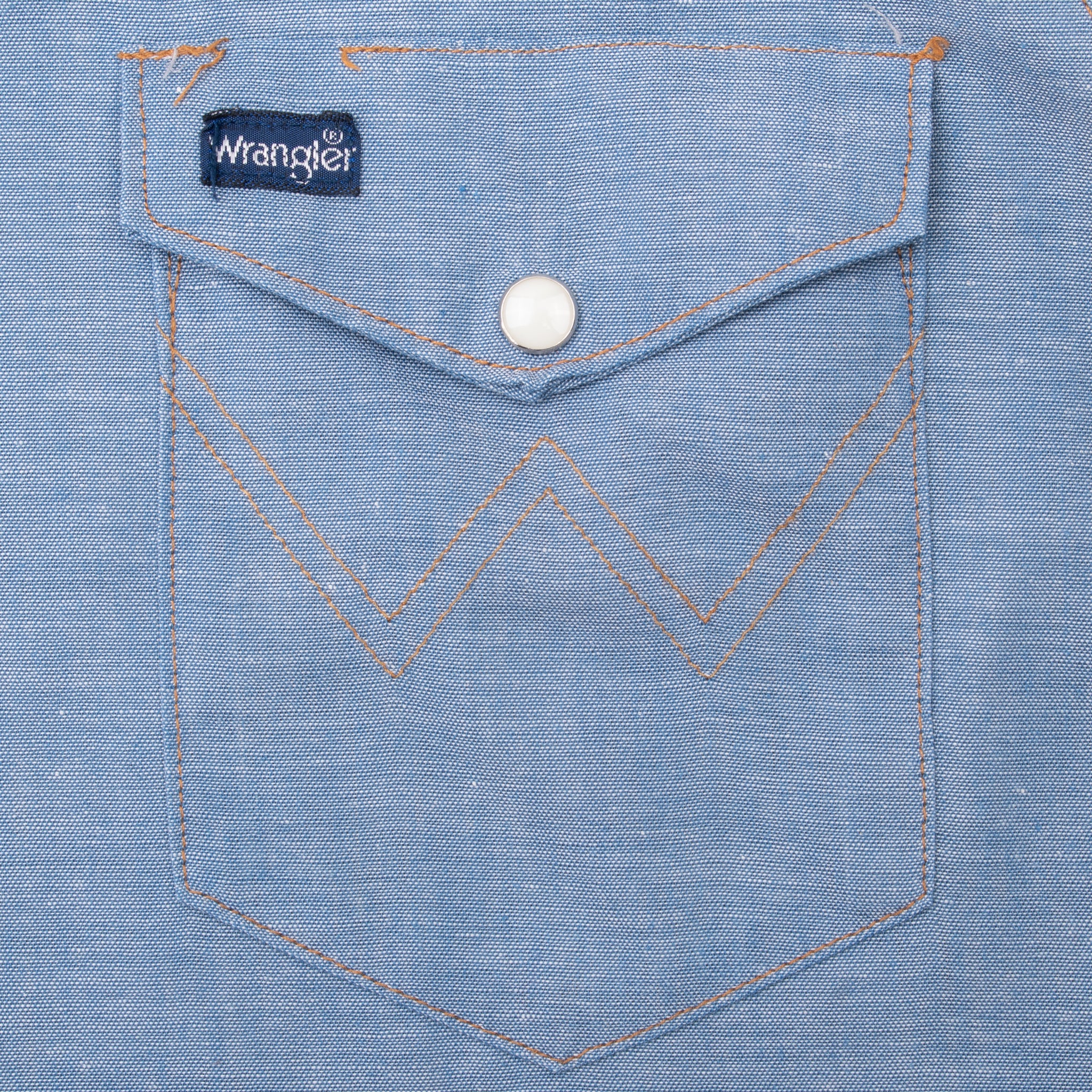 Wrangler chest pocket with pearl snap and orange W stitching
