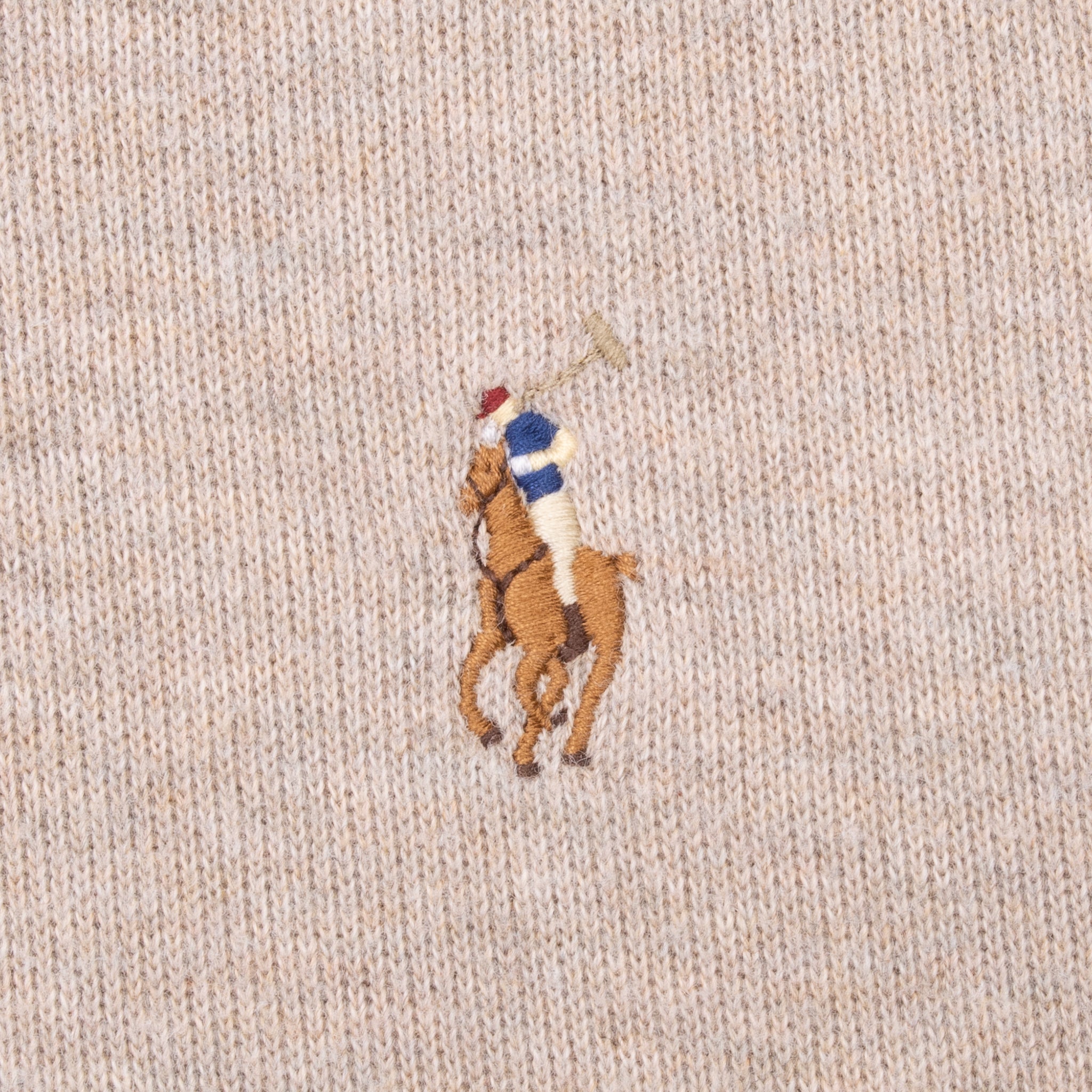 Close-up of multicolor Polo pony embroidery on beige knit fabric
