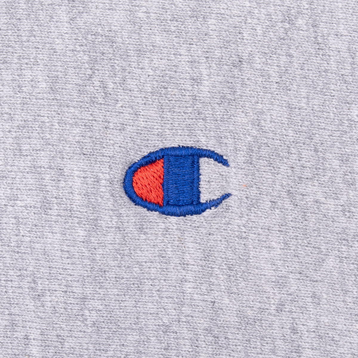 Close-up of blue and red Champion logo embroidery on grey sweatshirt