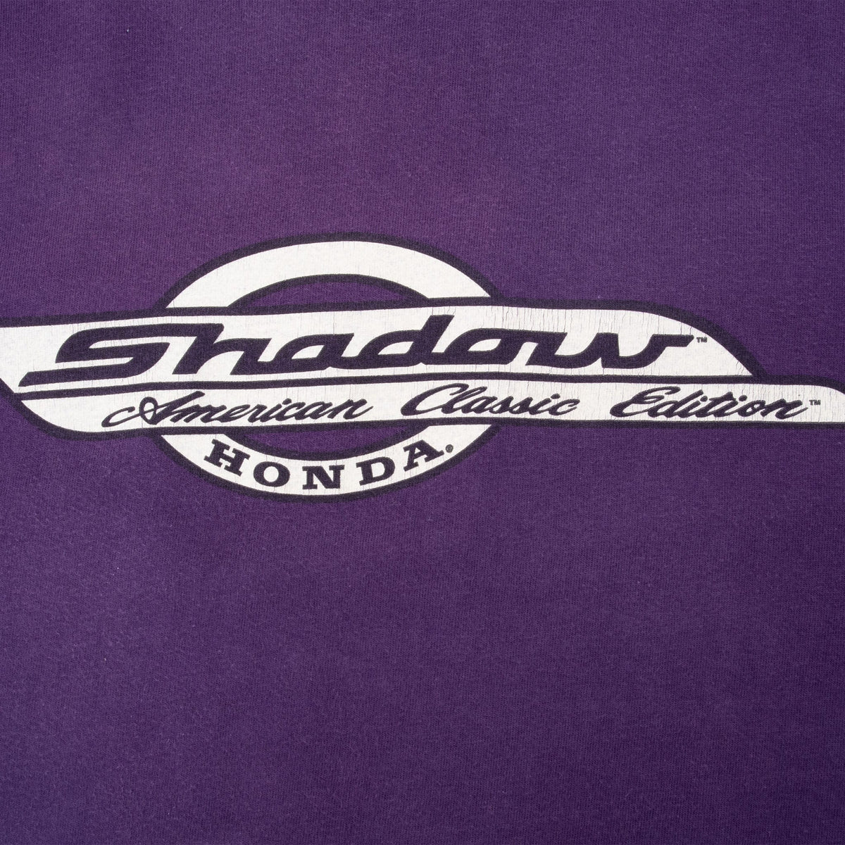Close-up of white and black Honda Shadow American Classic Edition chest print on purple fabric
