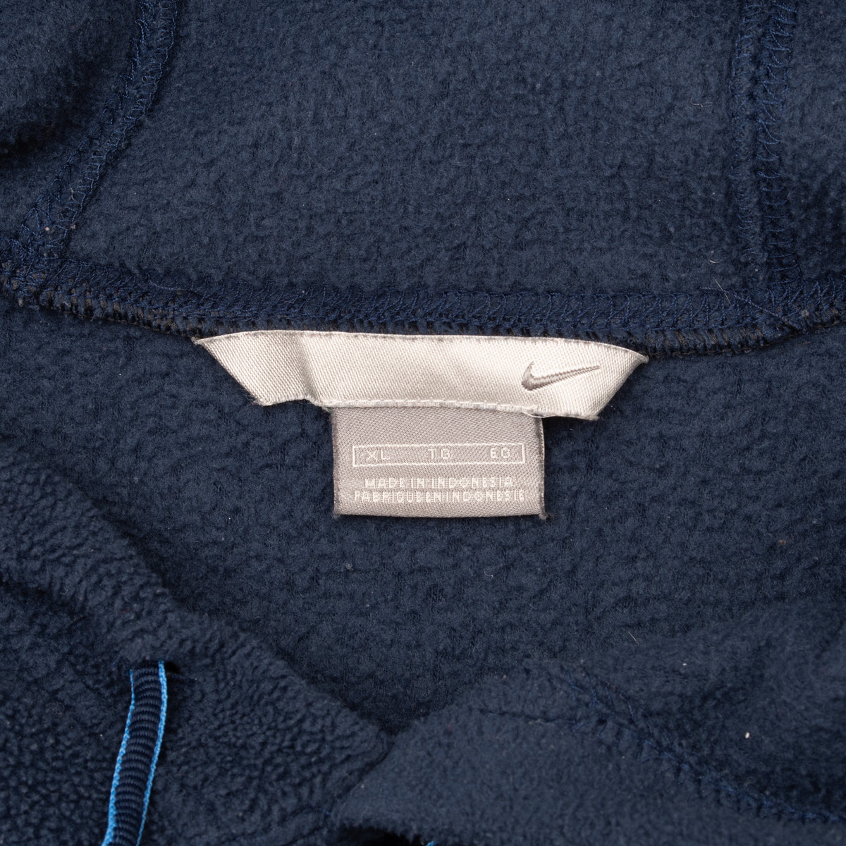 Close-up of Nike hoodie neck and care labels on navy blue fleece