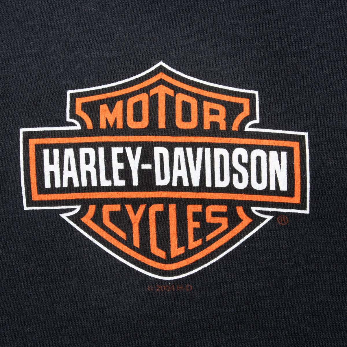 Close-up of orange and white Harley-Davidson Motor Cycles chest logo on black fabric